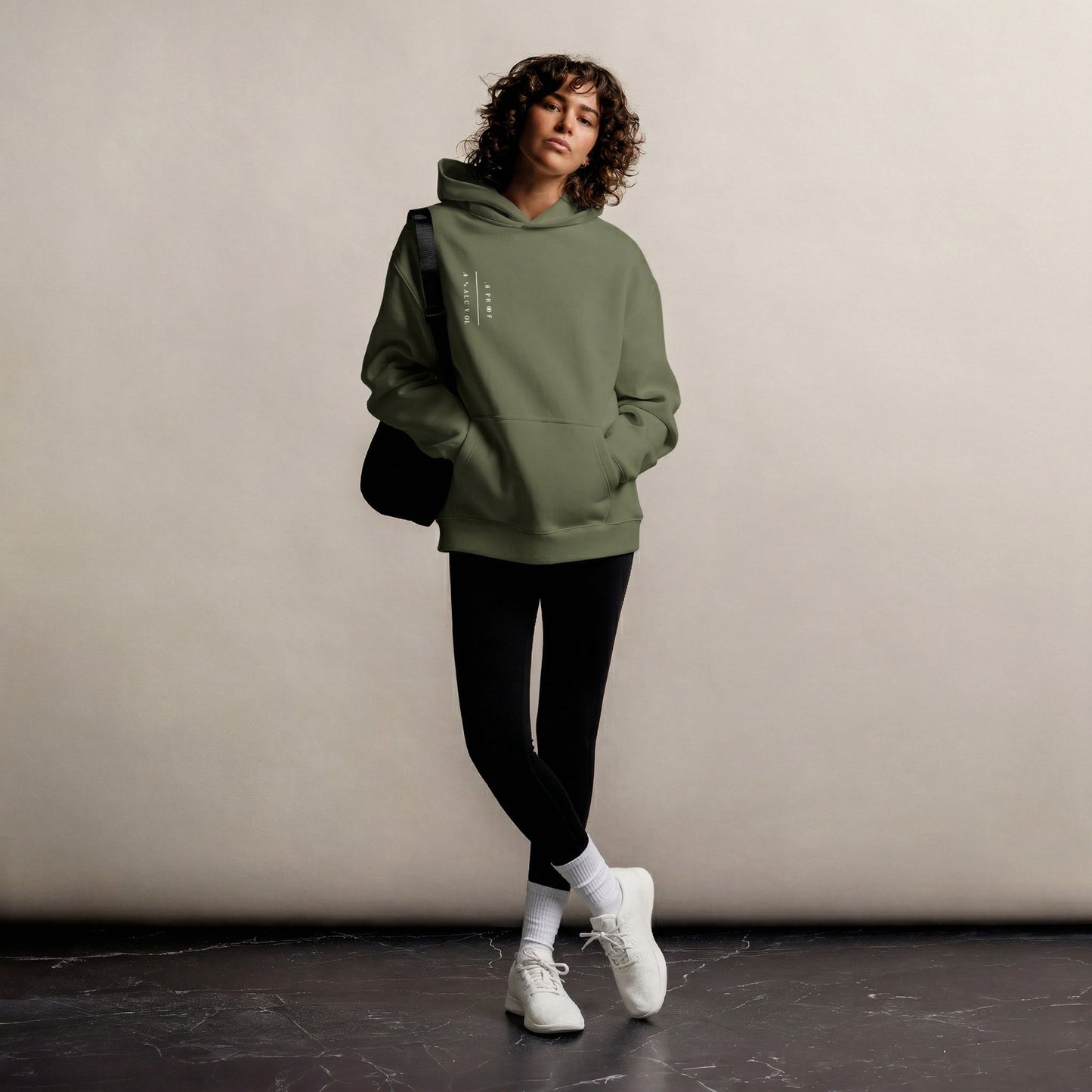 Person wearing a green hoodie and black pants against a plain background